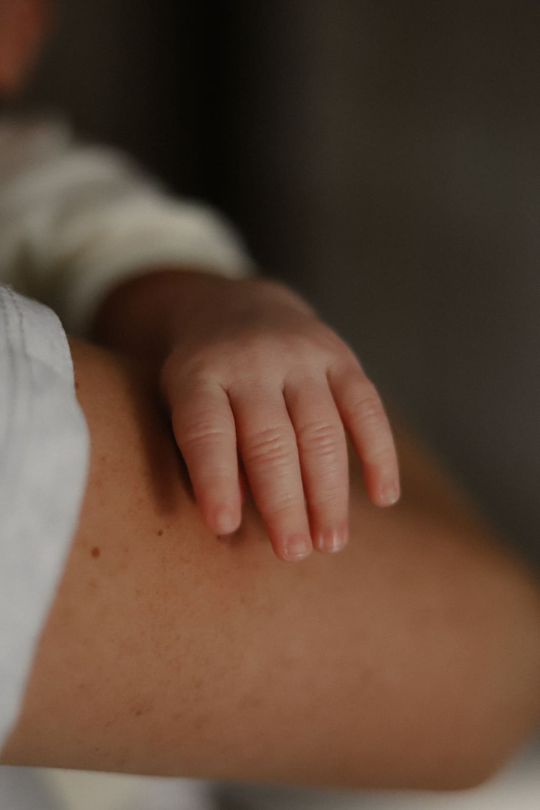 Main de nouveau-né posée sur l’épaule de sa mère