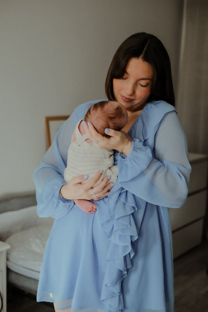 Maman en robe bleue portant son nouveau-né